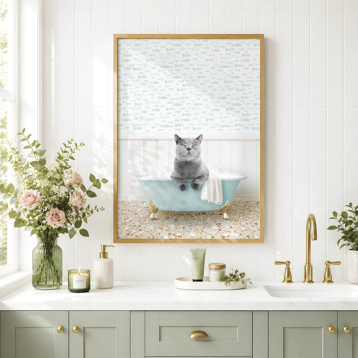A framed image of a gray cat sitting in a blue bathtub, surrounded by flowers and a green vase, is displayed on a white tiled wall above a bathroom sink.