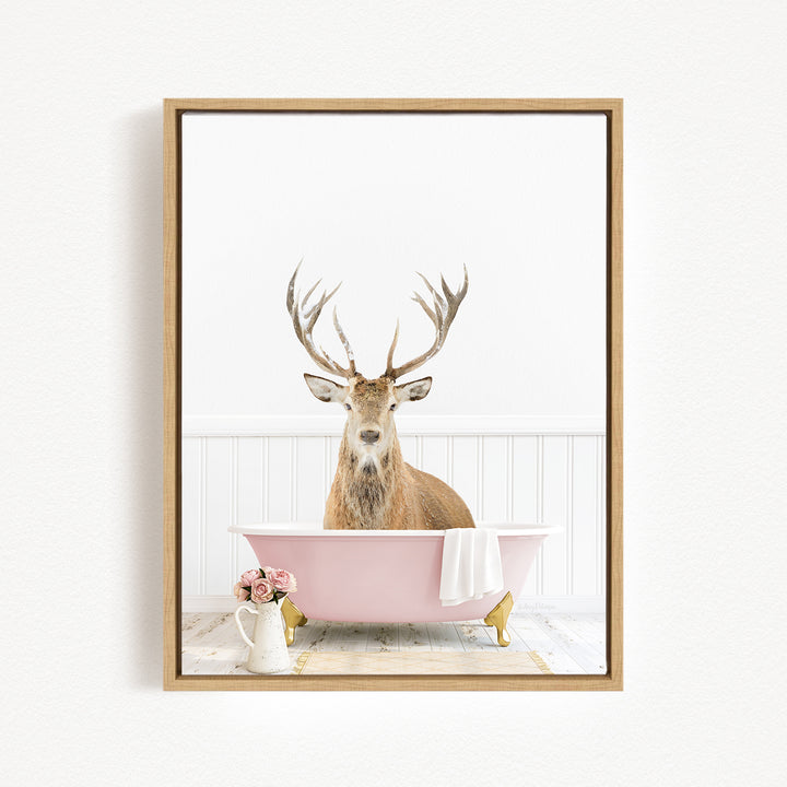 A deer with antlers sits in a pink bathtub, surrounded by pink flowers and a white vase.