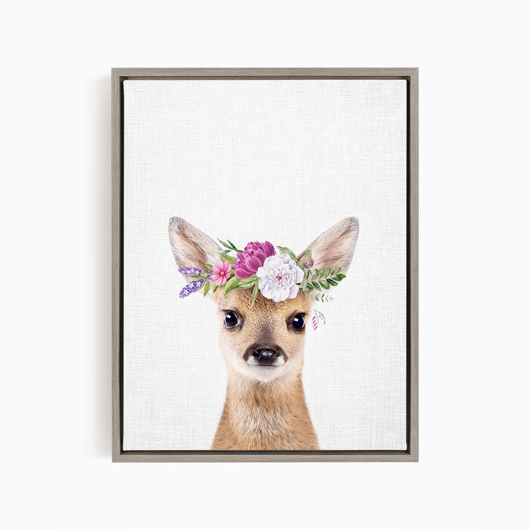 A deer wearing a floral crown on its head, with a neutral background.