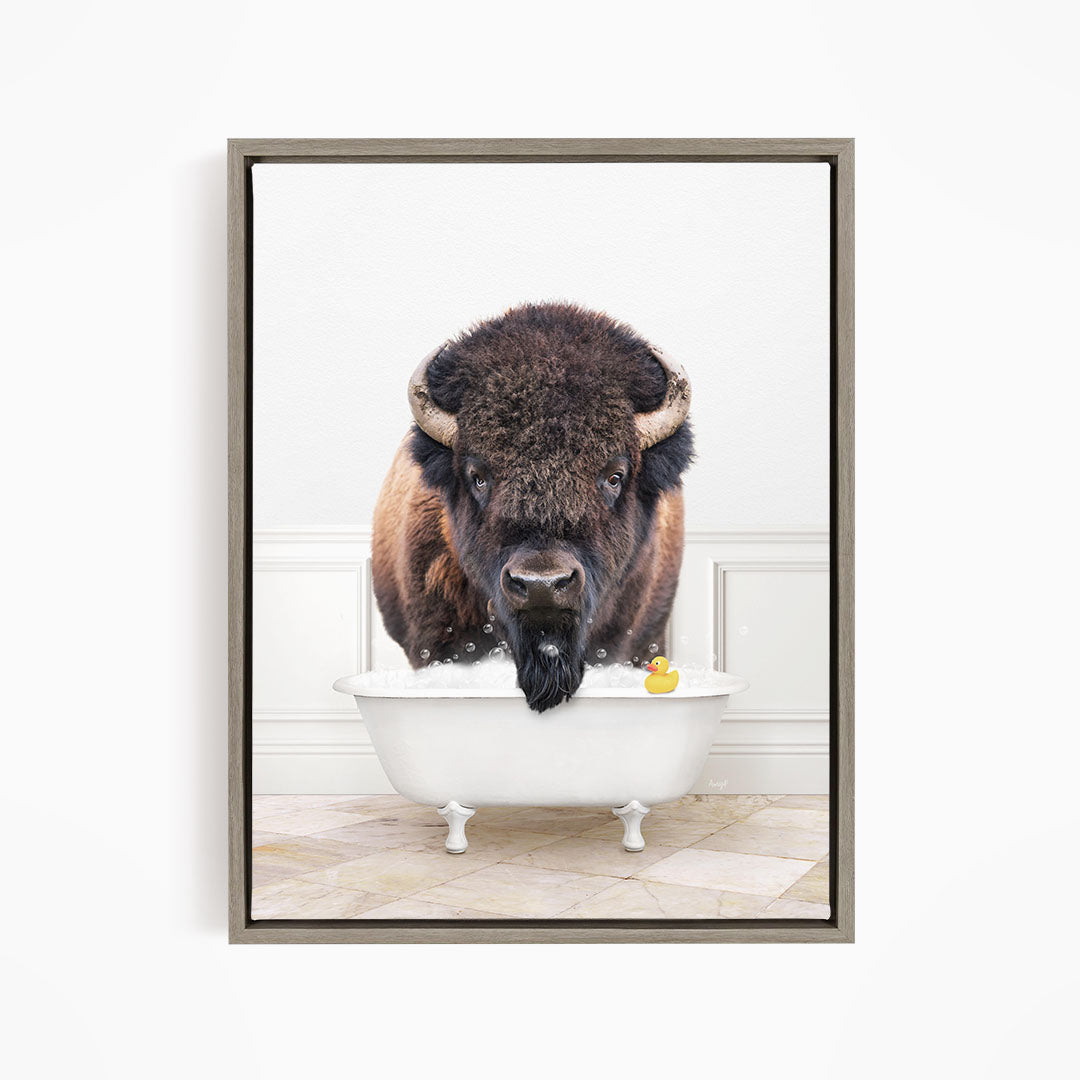 A buffalo with a long beard is sitting in a white bathtub, with a rubber duck floating in the water.