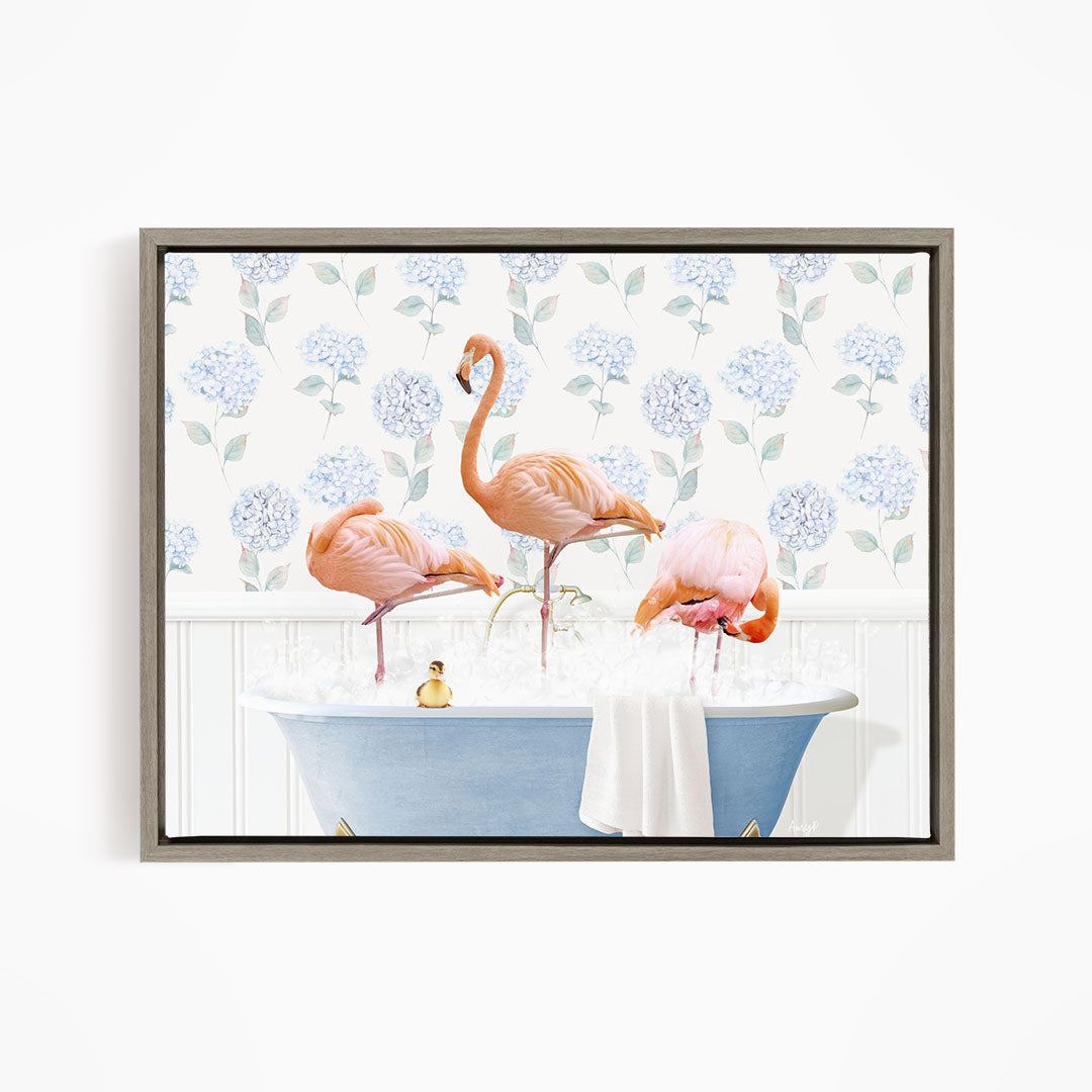 A framed image depicting three flamingos standing in a bathtub filled with water, surrounded by a floral patterned wall.