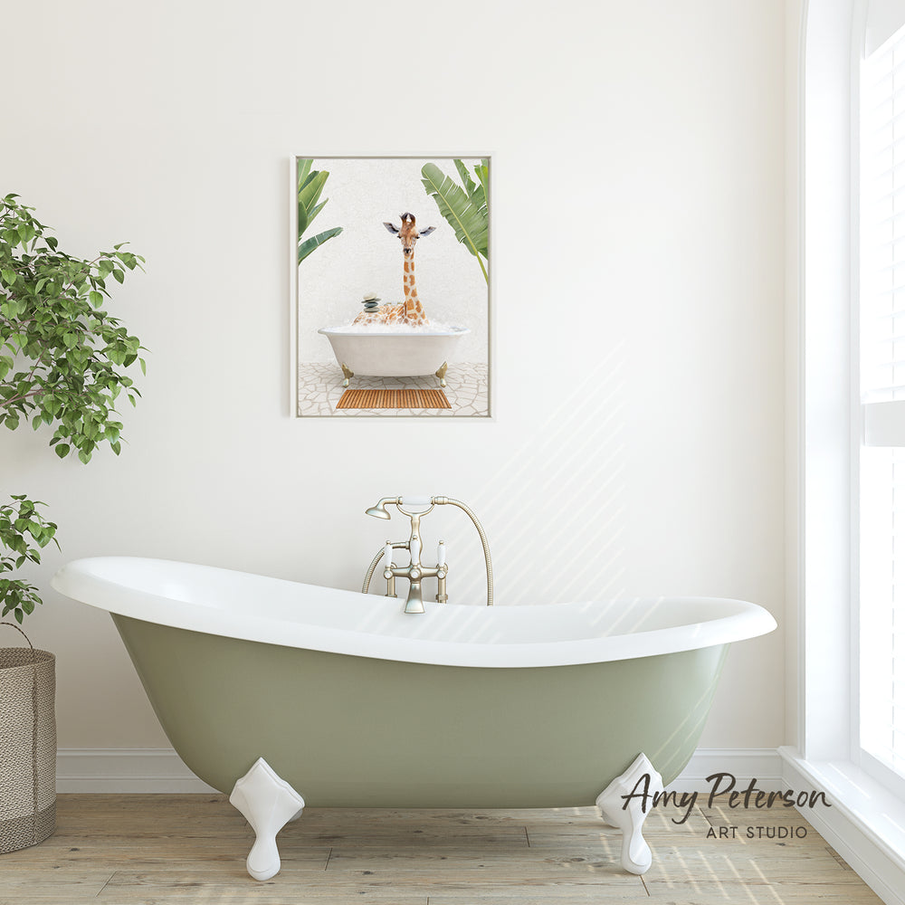 A green clawfoot bathtub with a gold faucet, set against a white wall with a framed image of a giraffe sitting in a bathtub.