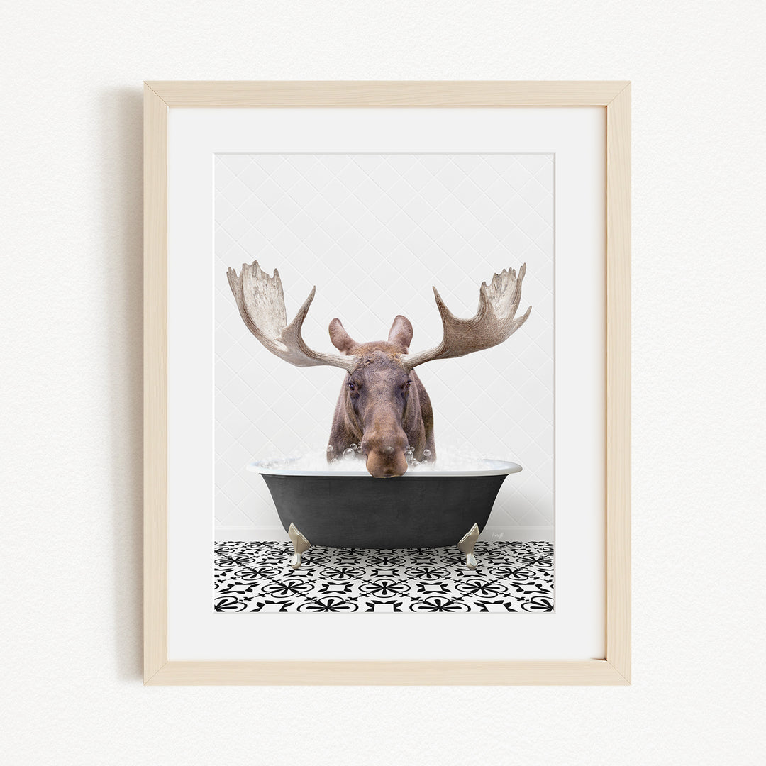 A moose with large antlers is sitting in a bathtub, surrounded by a black and white patterned floor.
