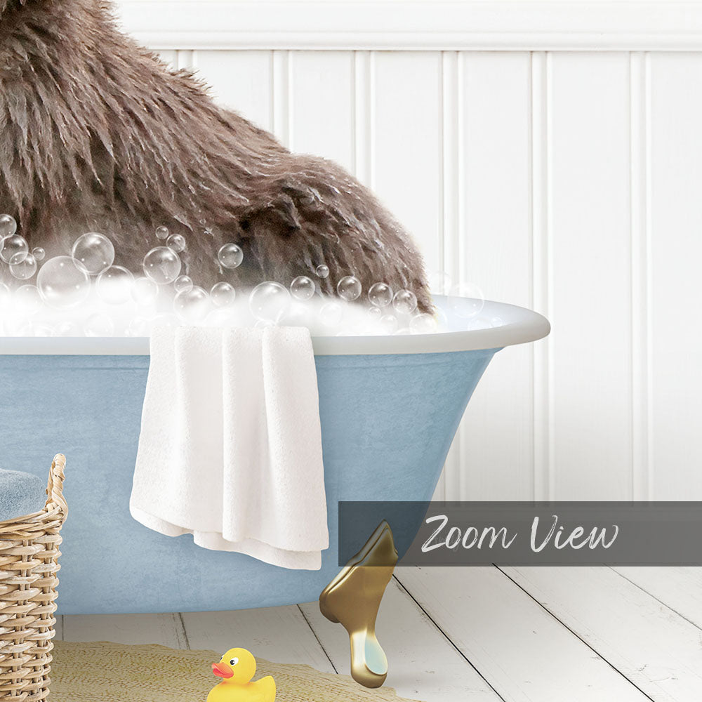 A fluffy brown dog is sitting in a blue bathtub filled with bubbles, surrounded by a yellow rubber duck and a white towel.