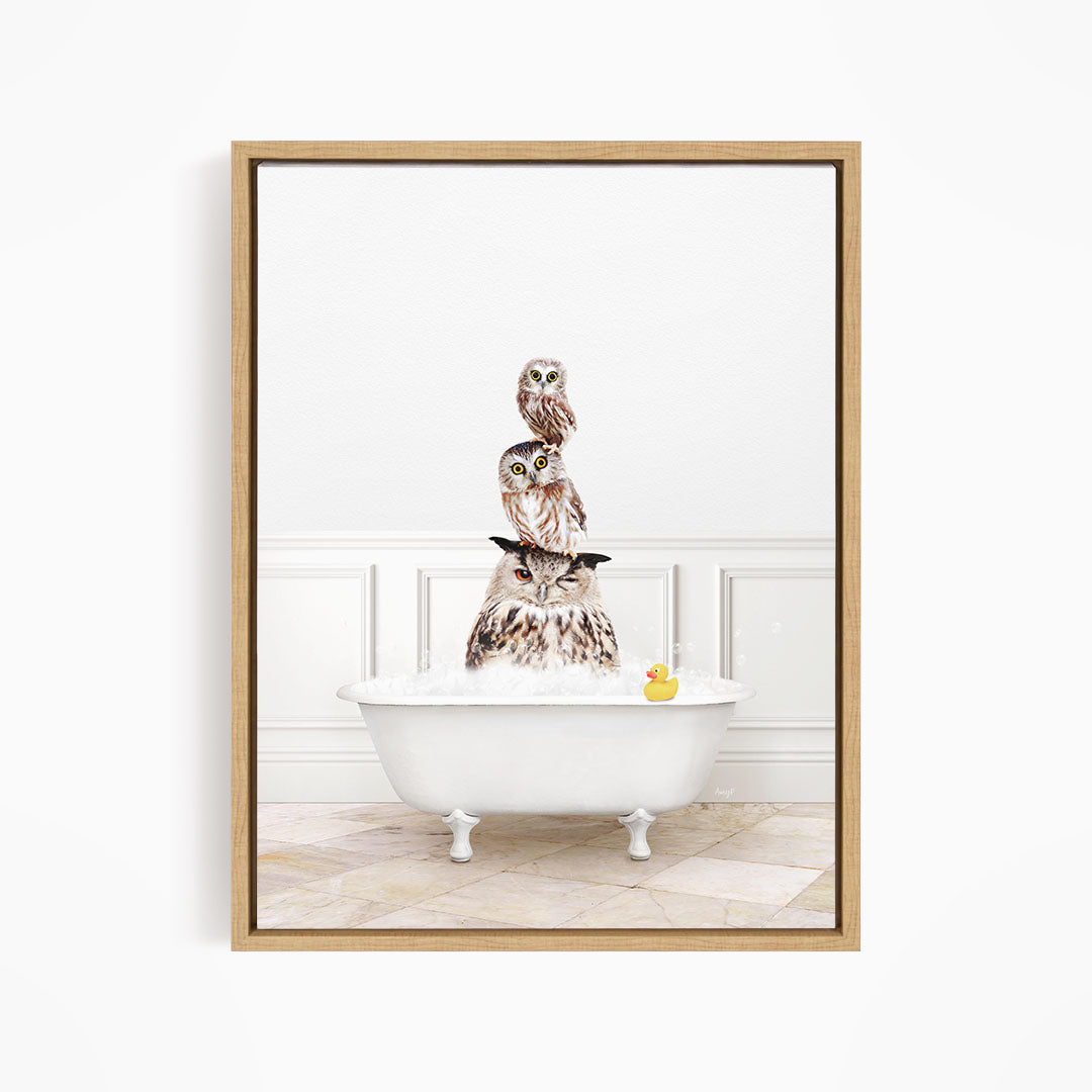 A framed image depicting three owls sitting on a white bathtub, with a rubber duck floating in the water.