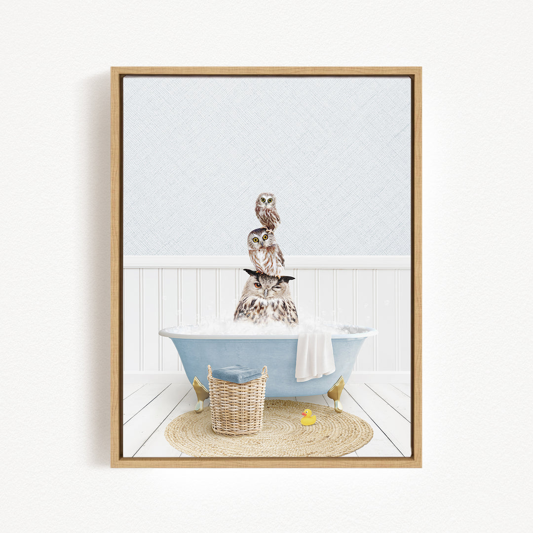 A framed image depicting a group of owls sitting in a bathtub filled with water, surrounded by a basket and a yellow rubber duck.