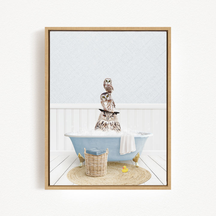 A framed image depicting a group of owls sitting in a bathtub filled with water, surrounded by a basket and a yellow rubber duck.