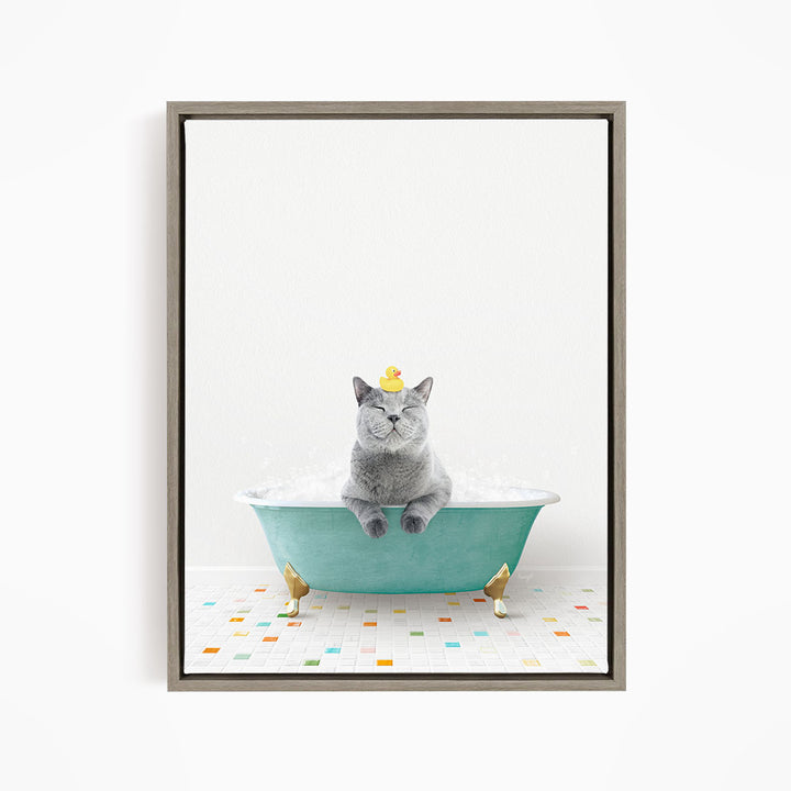 A gray cat sitting in a green bathtub, with a yellow rubber duck on its head, and a colorful tiled floor in the background.
