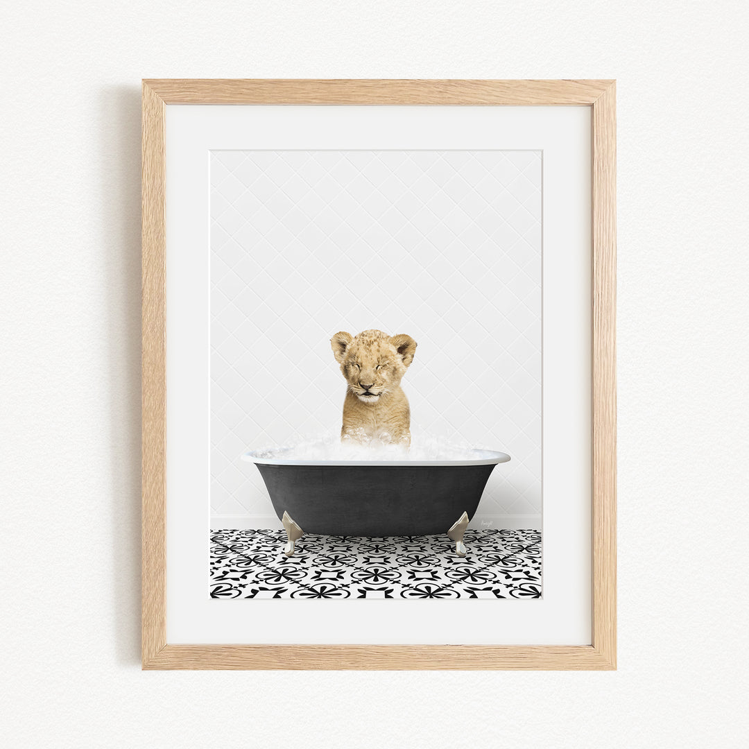 A young lion cub sitting in a bathtub filled with water, surrounded by a black and white patterned floor.