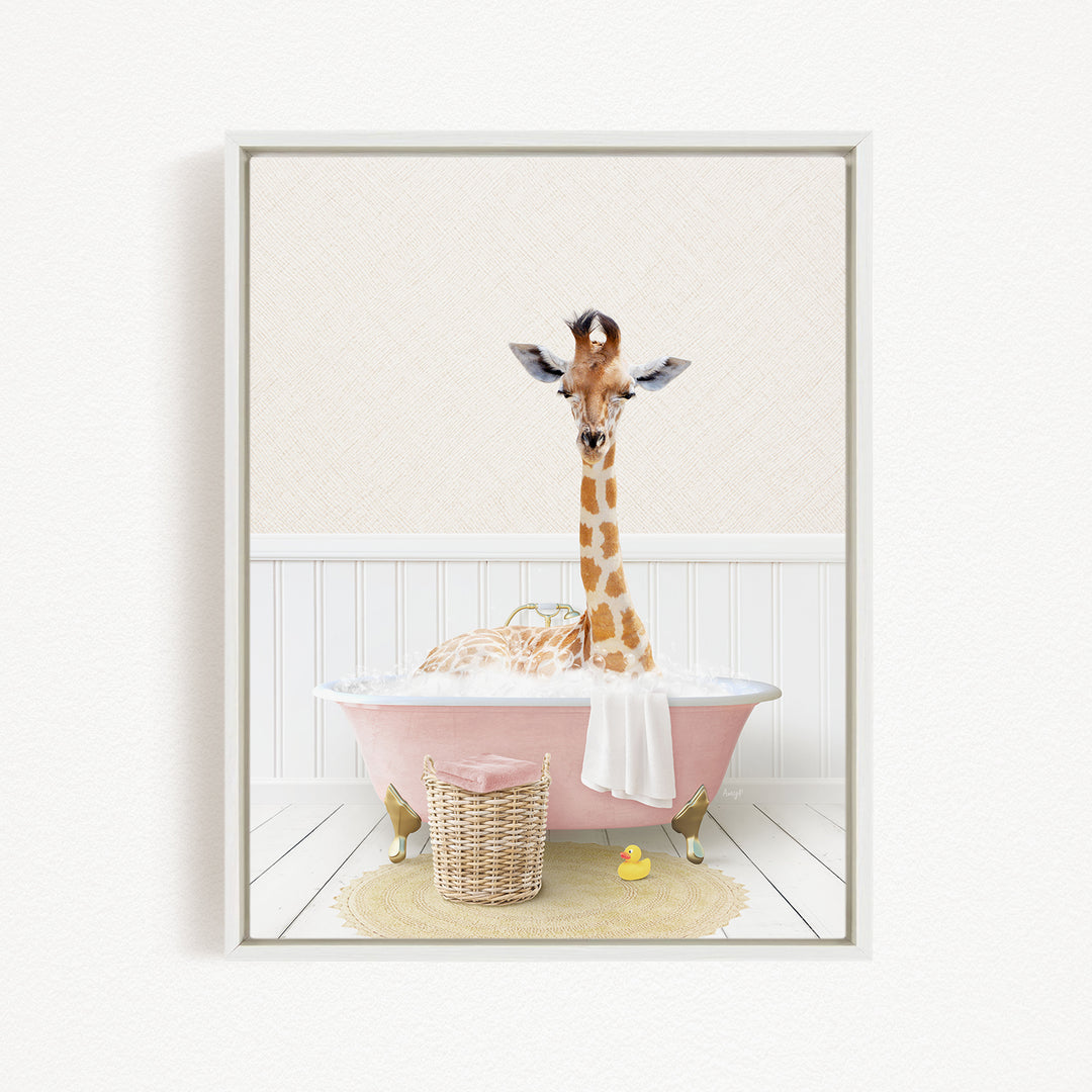 A giraffe is sitting in a pink bathtub filled with water, surrounded by a basket of rubber ducks and a towel.