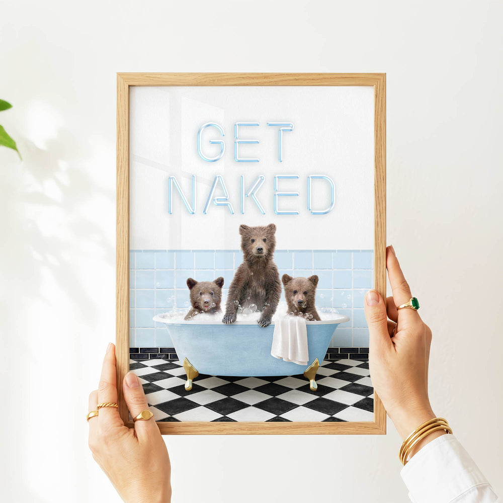 A person is holding up a framed image that features three bears sitting in a bathtub, with the text "GET NAKED" displayed above them.