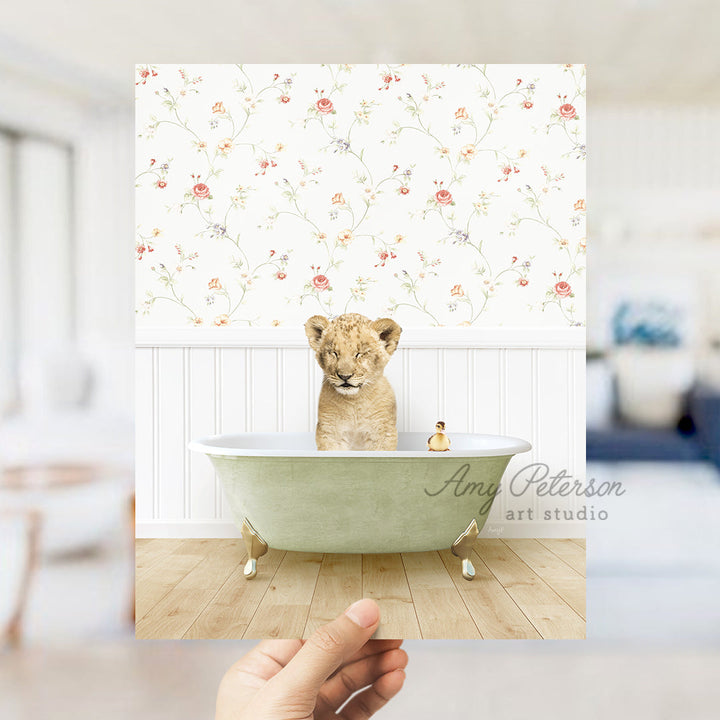 a hand holding up a photo of a baby lion in a bathtub