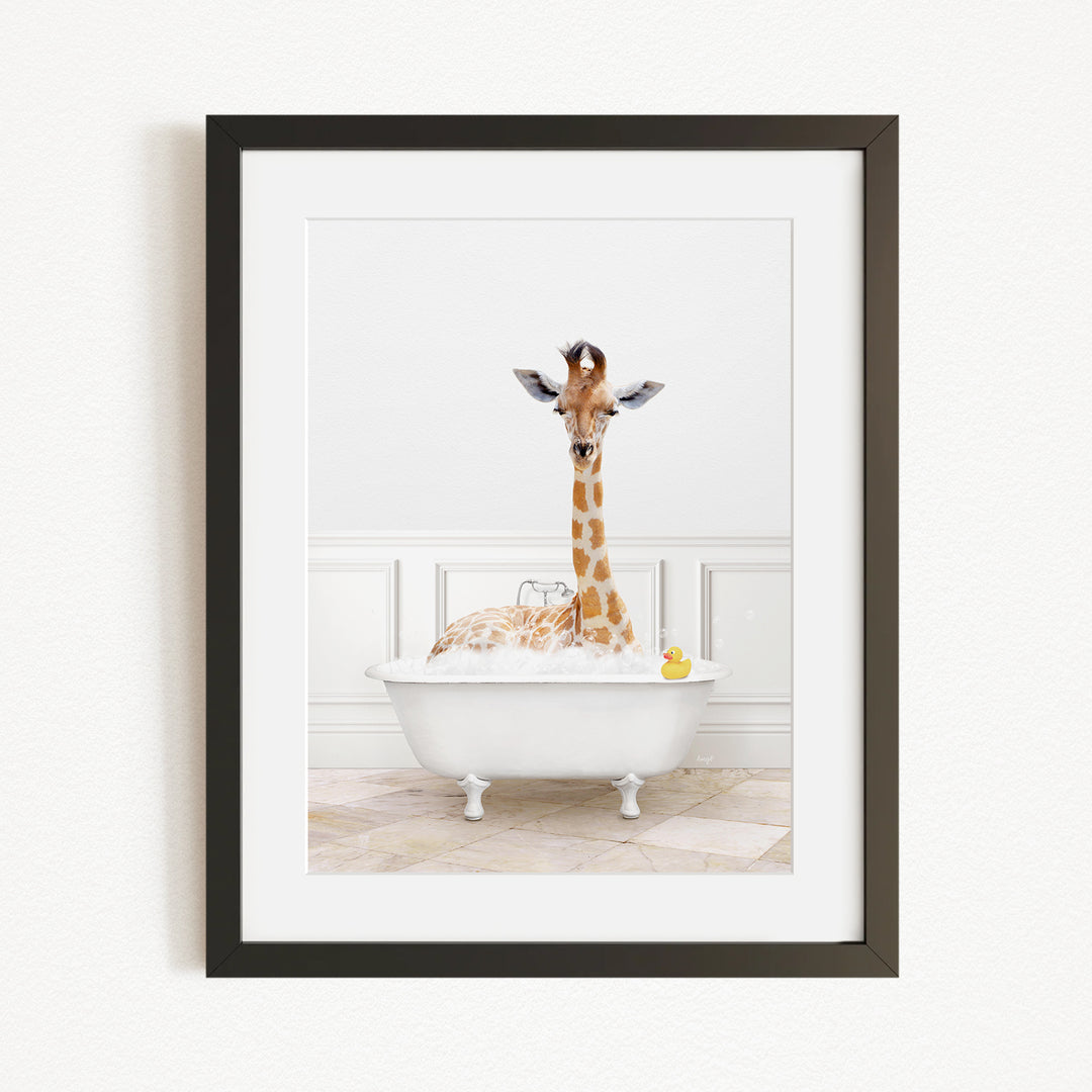 A giraffe is sitting in a white bathtub filled with bubbles, with a yellow rubber duck floating in the water.