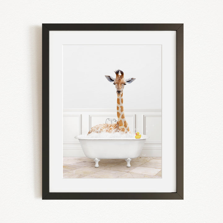 A giraffe is sitting in a white bathtub filled with bubbles, with a yellow rubber duck floating in the water.