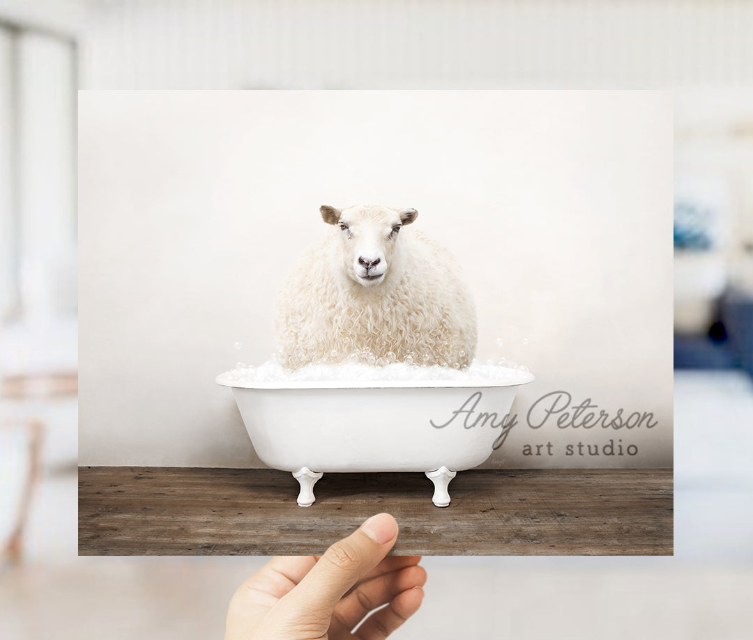 a hand holding up a card with a sheep in a bathtub