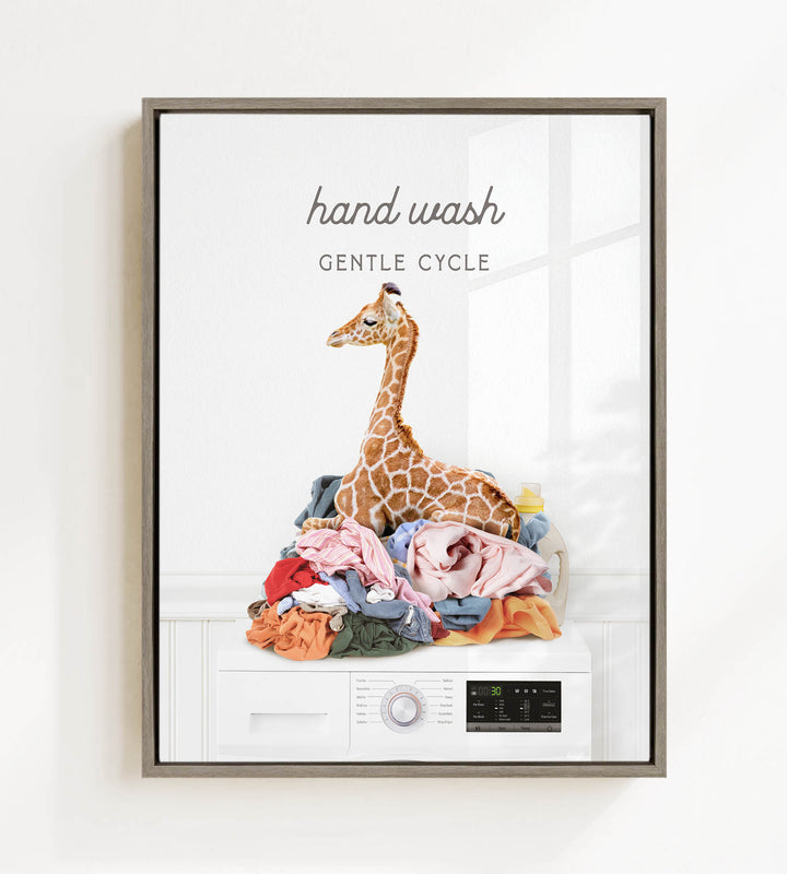 A giraffe sitting on a pile of laundry in front of a washing machine, with the text "hand wash gentle cycle" above the image.