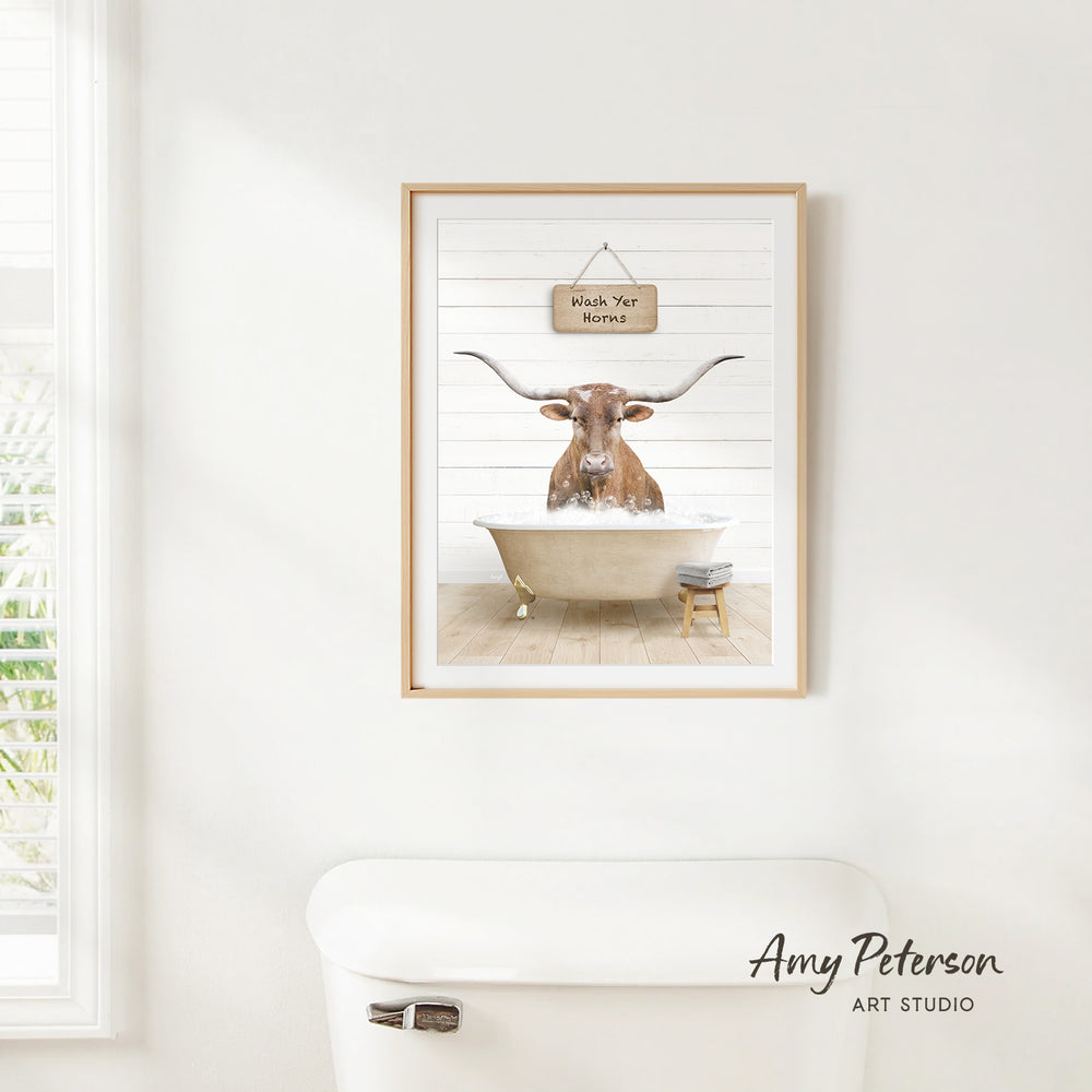 A framed image of a bull with horns sitting in a bathtub, accompanied by a sign that says "Worms Your Horns".