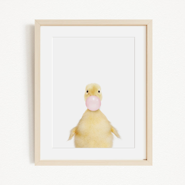 A cute yellow duck blowing a bubble with a pink bubble gum bubble.