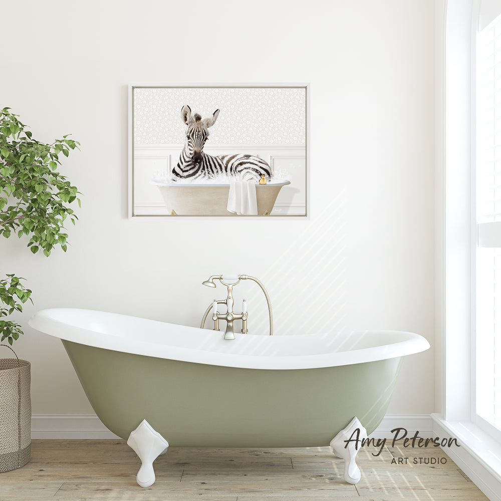 A framed image of a zebra sitting in a bathtub is displayed on the wall above a green clawfoot bathtub in a bathroom.