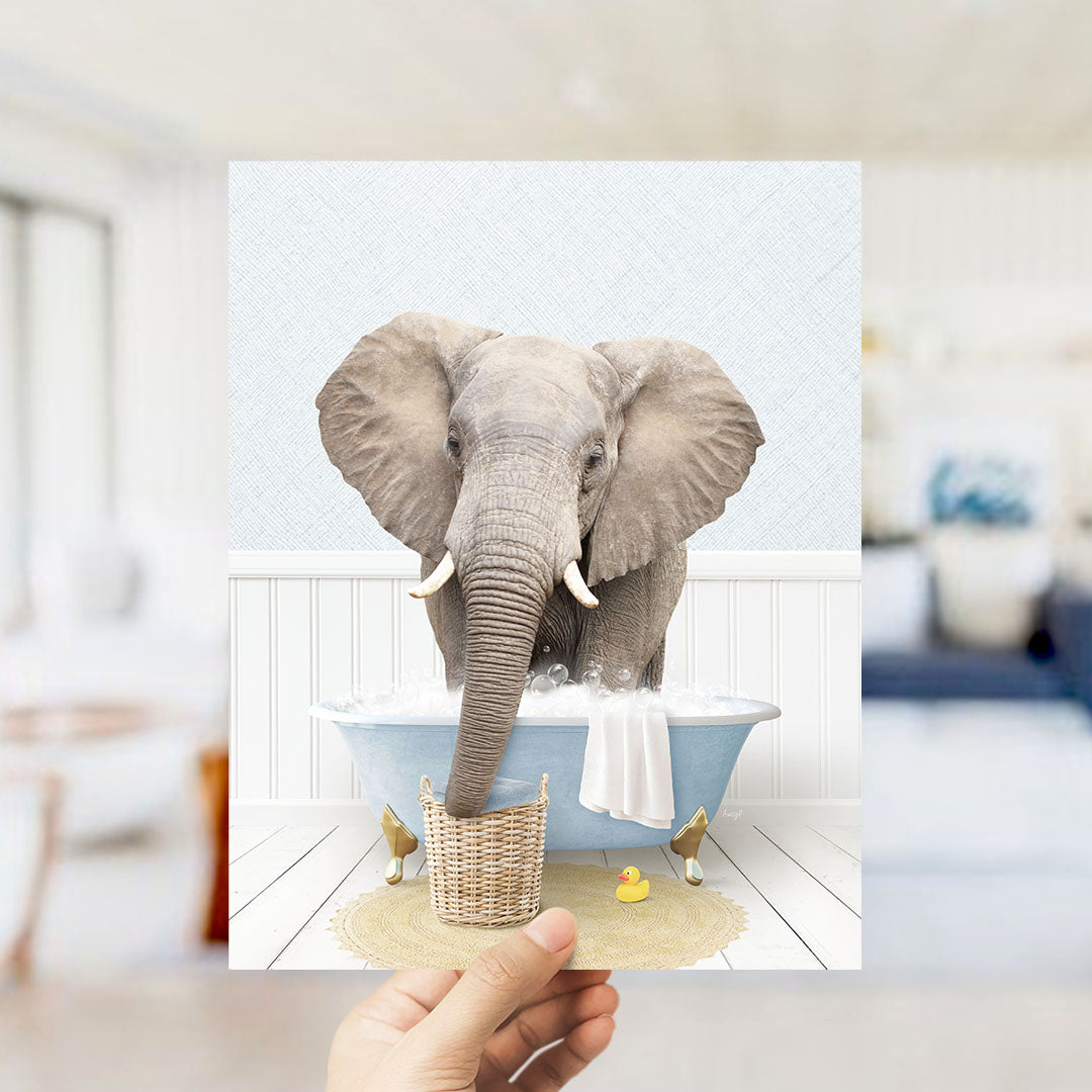 A large gray elephant is sitting in a blue bathtub filled with water, surrounded by a yellow rubber duck and a basket.