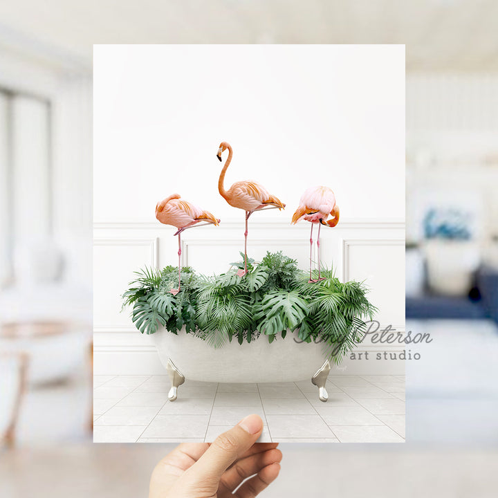 a hand holding a card with three flamingos in a bathtub