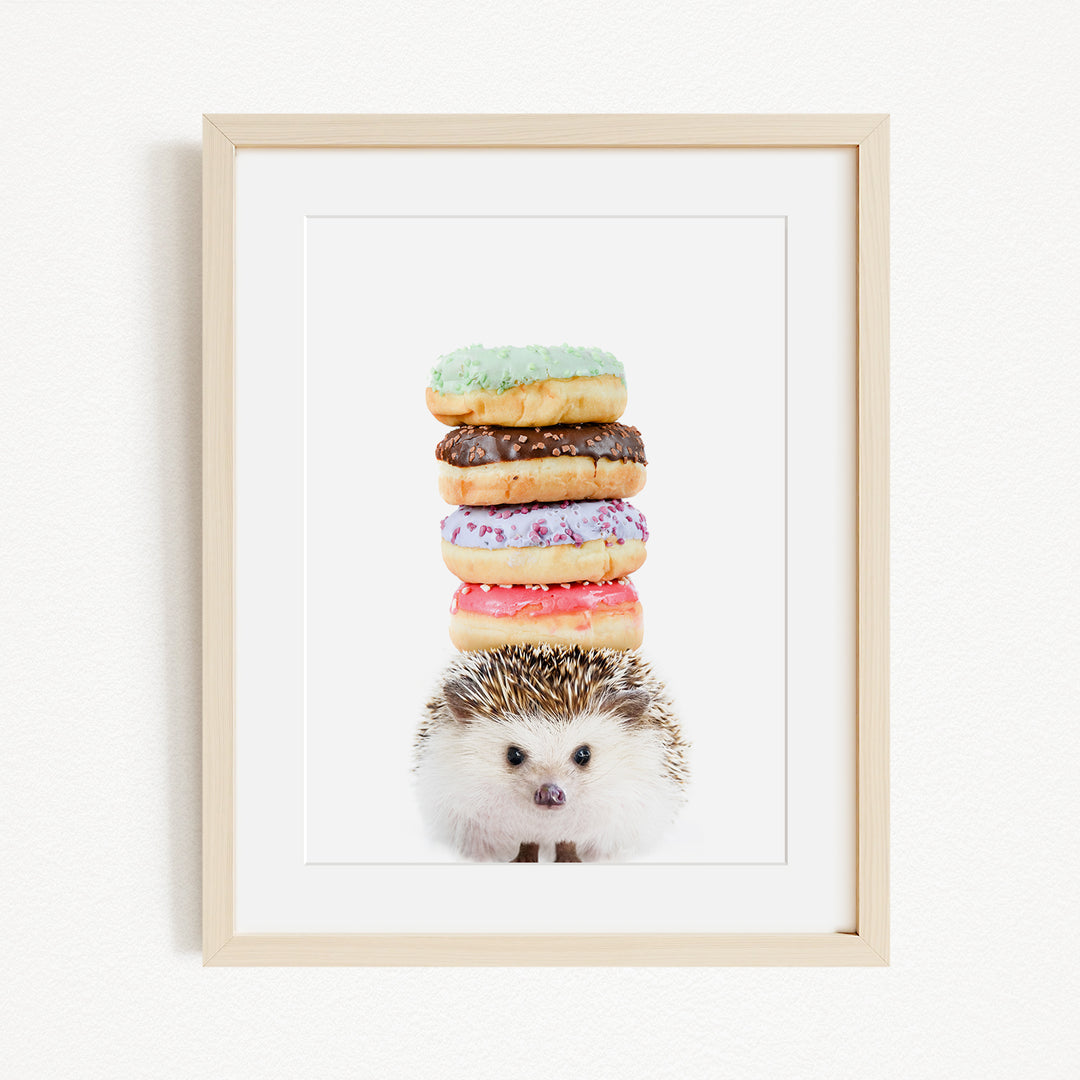 A framed image of a hedgehog standing in front of a stack of colorful donuts.