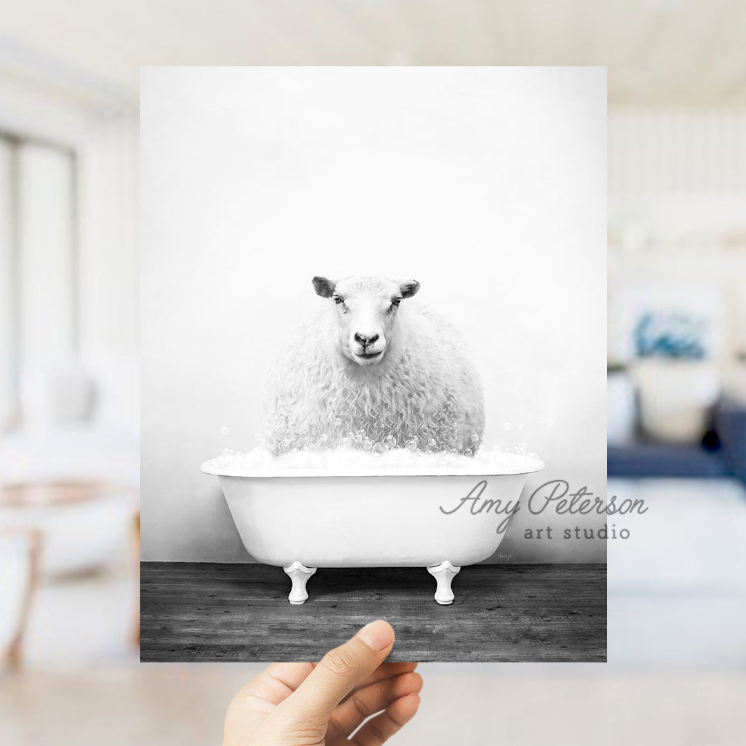 a hand holding a card with a sheep in a bathtub