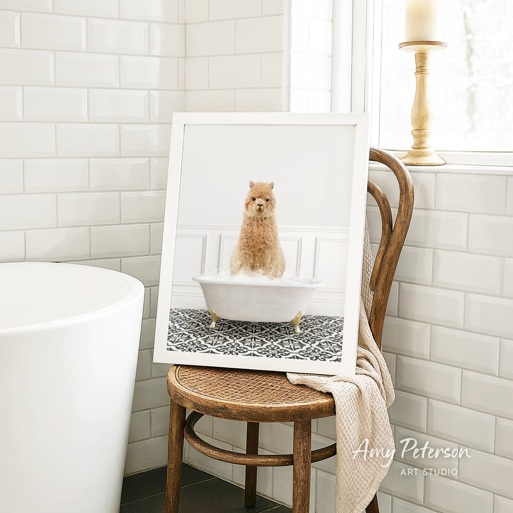 A framed image of a small dog sitting in a bathtub, surrounded by a patterned tile design, is displayed on a wooden chair in a bathroom setting.