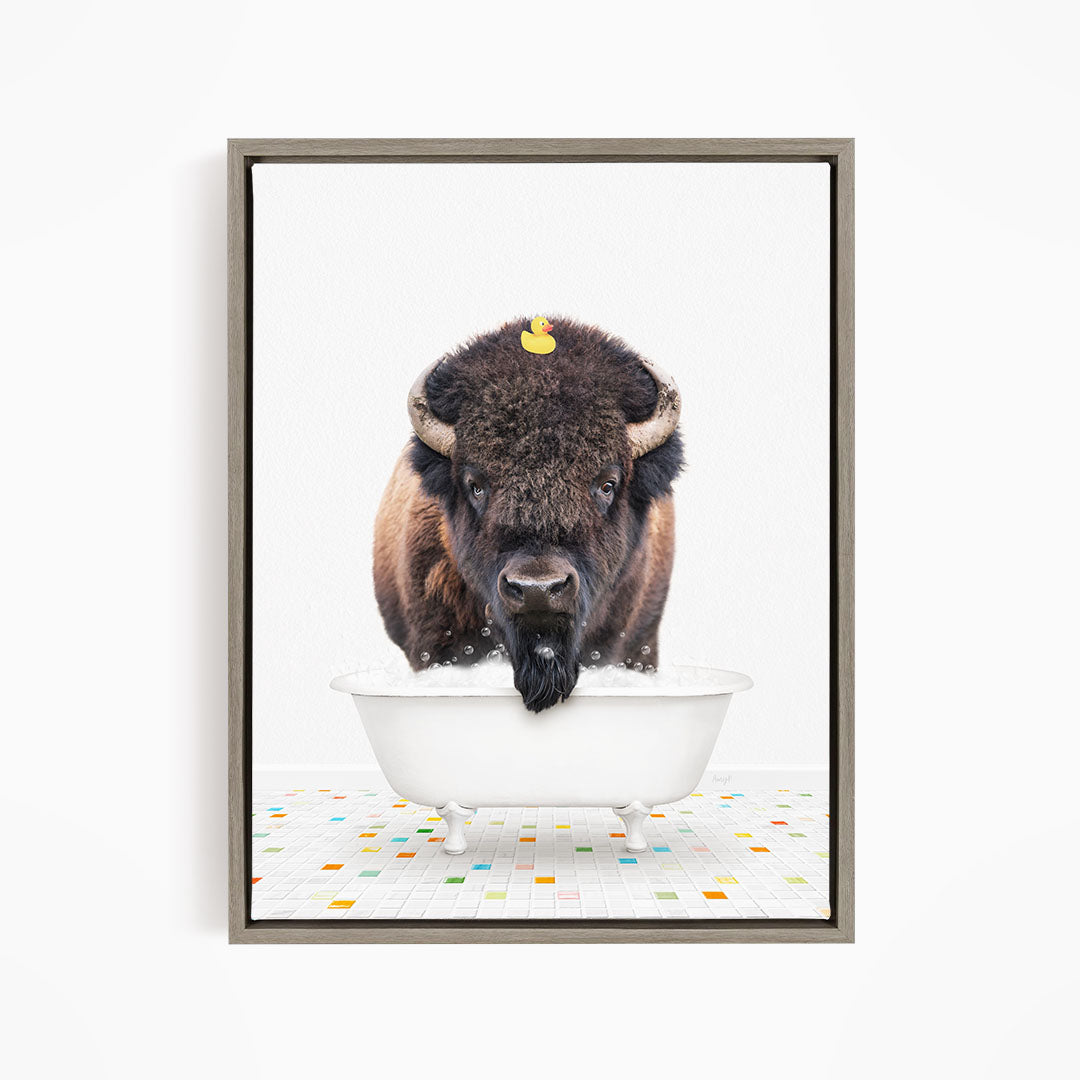 A buffalo standing in a white bathtub, with a yellow rubber duck on its head.