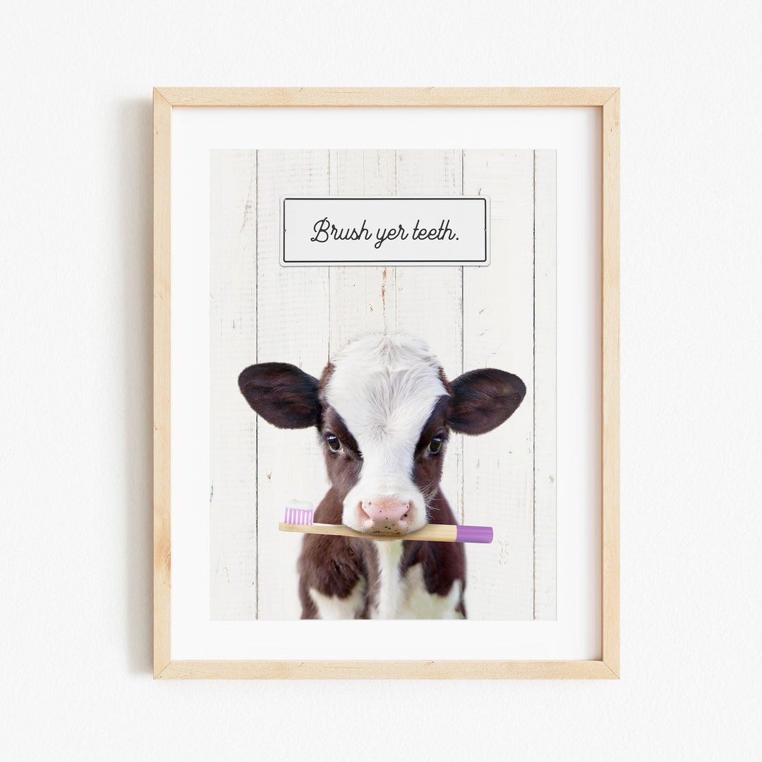 A framed image of a cow holding a toothbrush in its mouth, with the text "Brush yer teeth" above it.