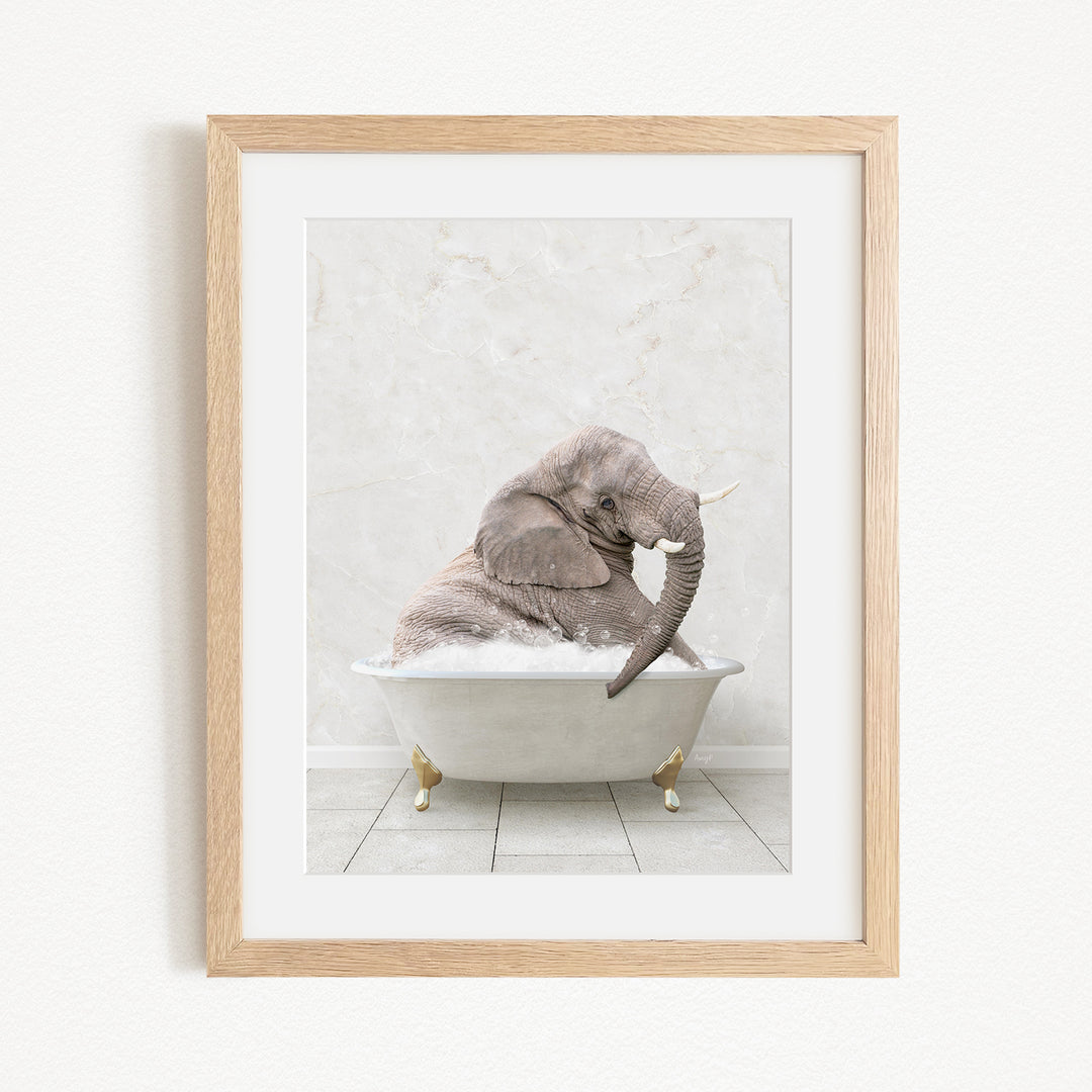 A gray elephant is sitting in a white bathtub, with its trunk raised and appearing to be enjoying the bath.