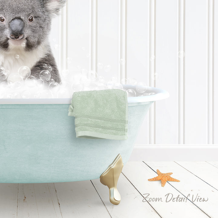 A koala bear sitting in a bathtub filled with bubbles, with a towel and starfish nearby.
