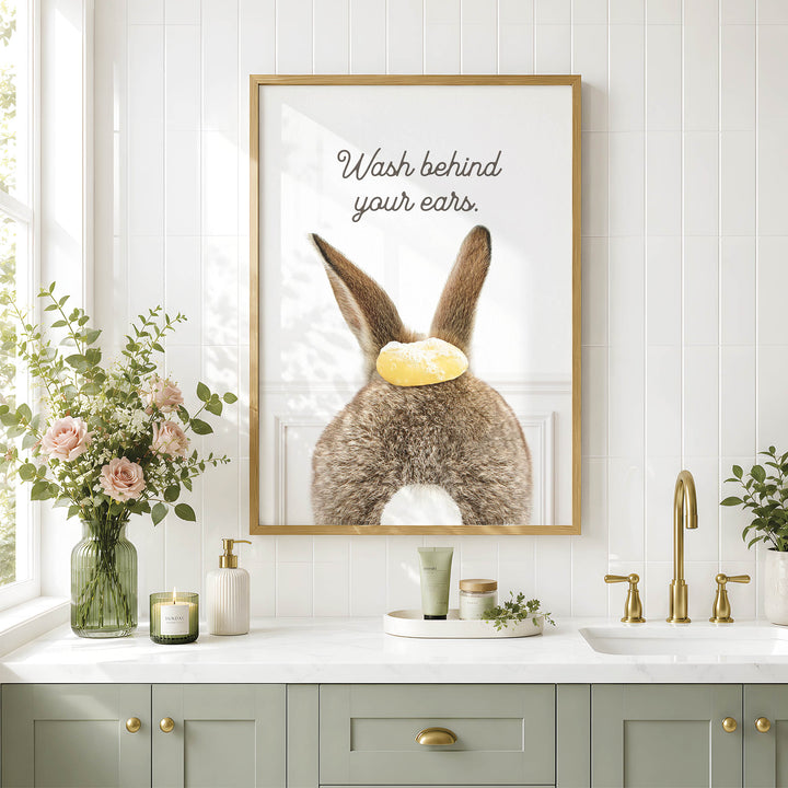 a bathroom with a framed poster of a rabbit's ears, a vase of flowers, and a sink with a green cabinet below it.