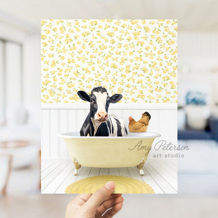 a person holding up a picture of a cow in a bathtub