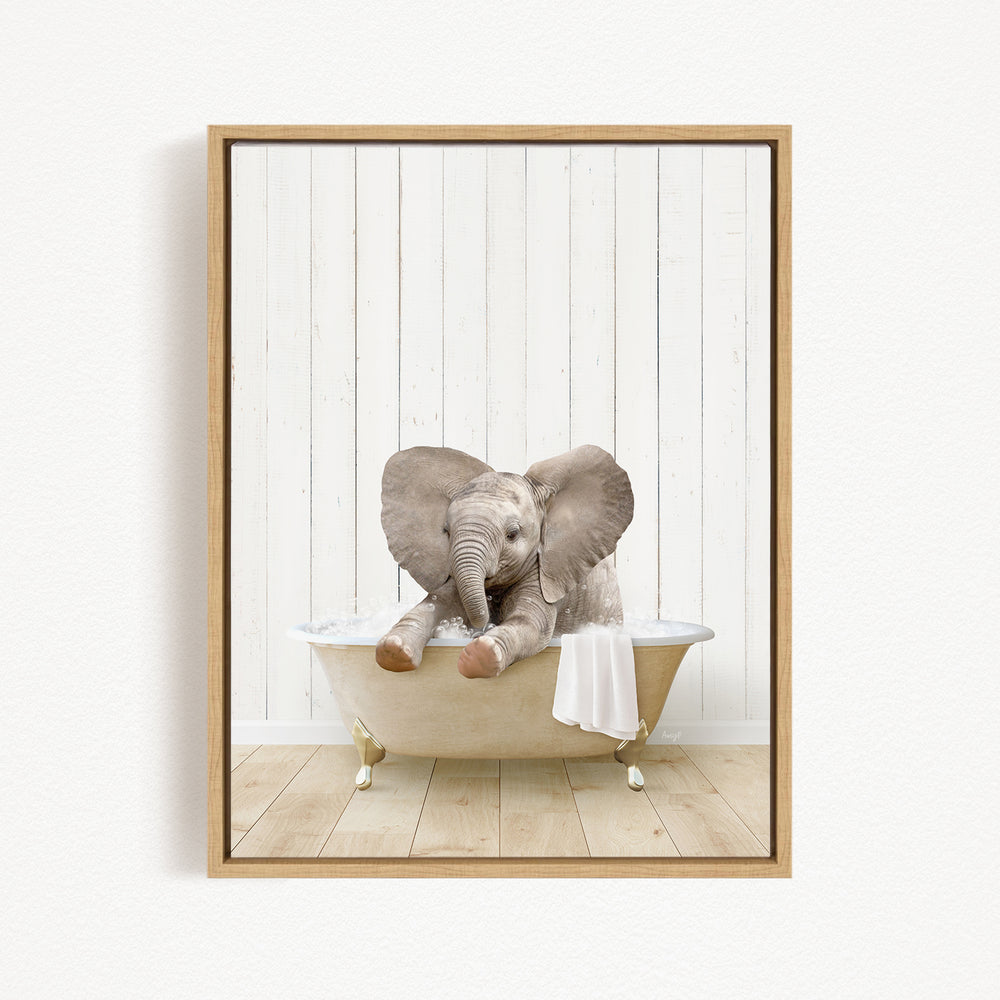 A baby elephant sitting in a bathtub, with its trunk in its mouth, against a white wooden wall.