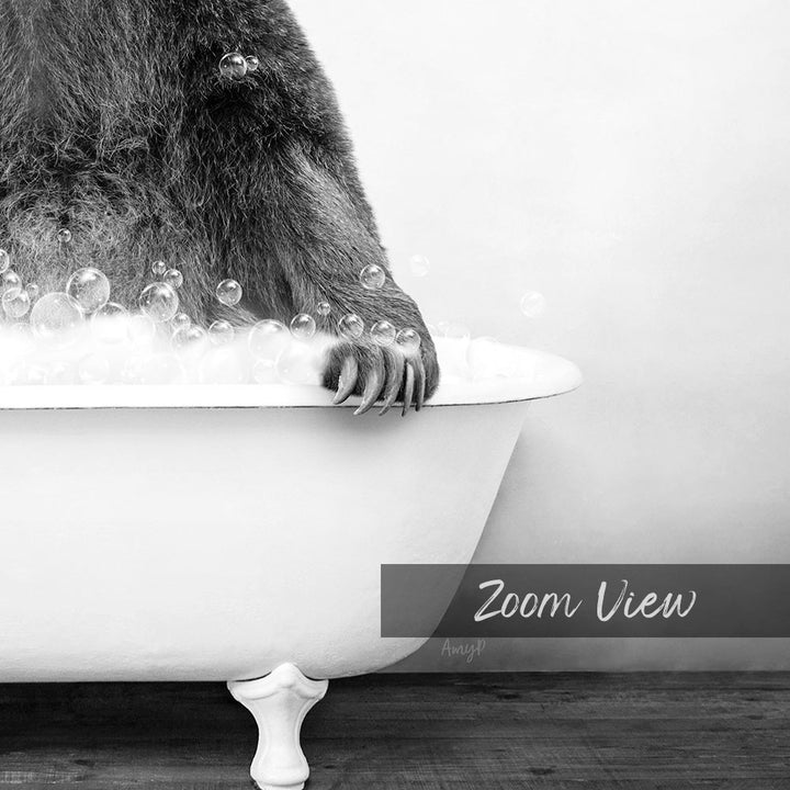 A close-up black and white image of a bear's paw resting on the edge of a bathtub filled with bubbles.