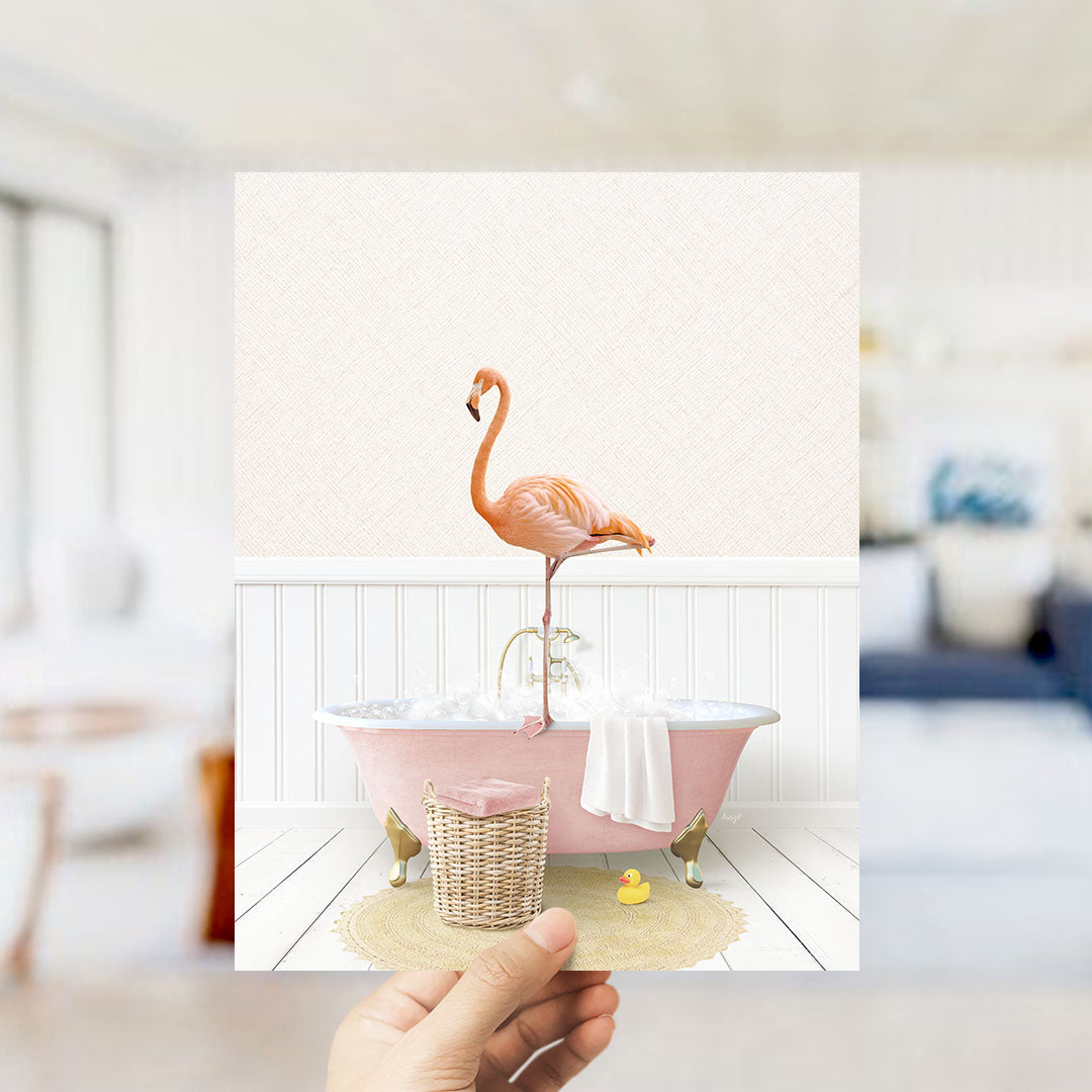 A pink flamingo standing on a pink bathtub filled with bubbles, with a basket of bath toys and a yellow rubber duck nearby.
