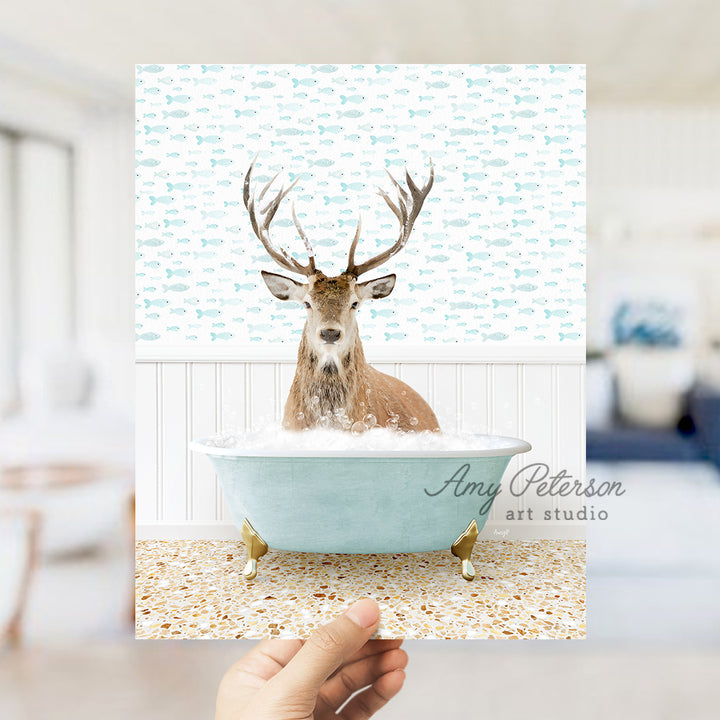 a hand holding up a photo of a deer in a bathtub