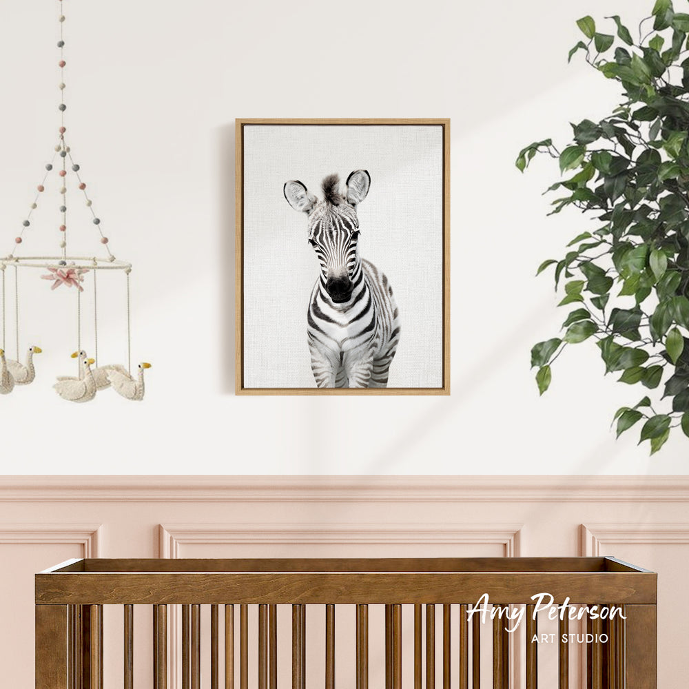 a wooden crib with a framed picture of a zebra hanging on the wall above it.