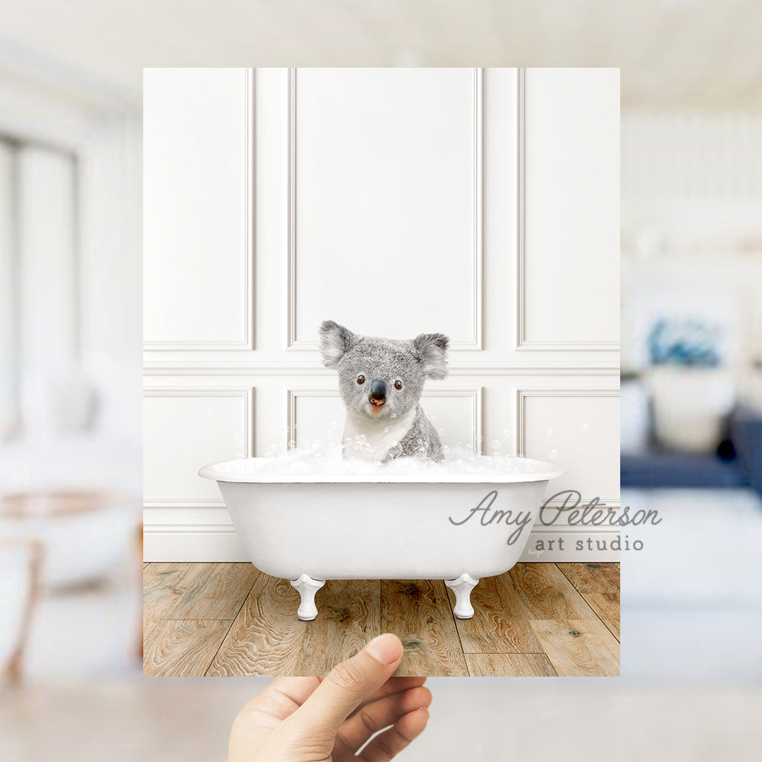 a hand holding a photo of a koala in a bathtub