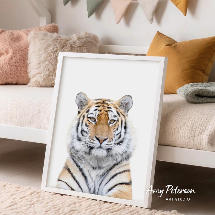 A framed photograph of a tiger's face is displayed in a room with a white bed and colorful pillows.