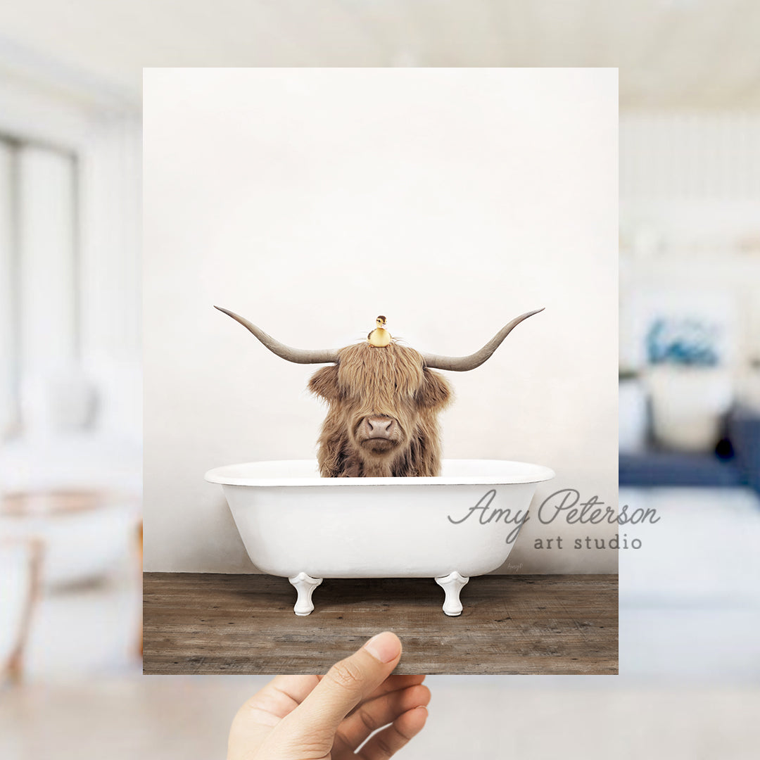 a hand holding up a photo of a bull in a bathtub