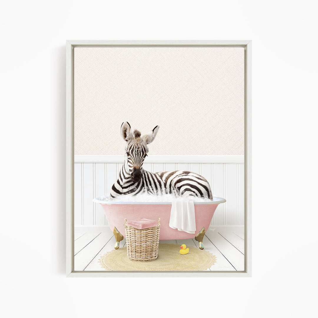 A zebra is sitting in a pink bathtub, surrounded by a yellow rubber duck and a wicker basket.