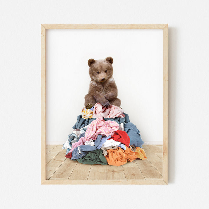 a brown teddy bear sitting on top of a pile of clothes