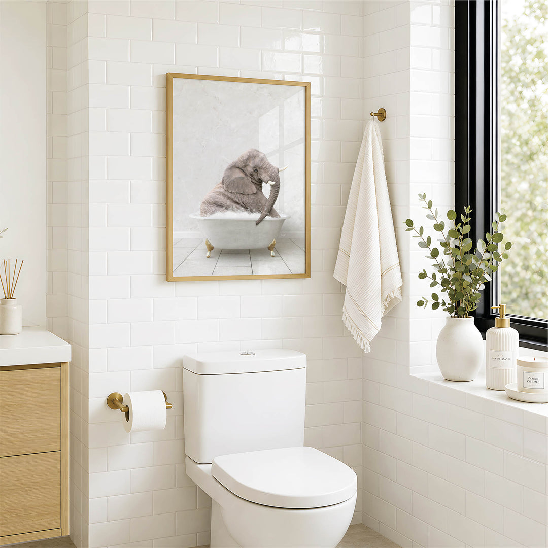 A bathroom with a white toilet, a framed picture of an elephant in a bathtub, and a window with greenery on the sill.