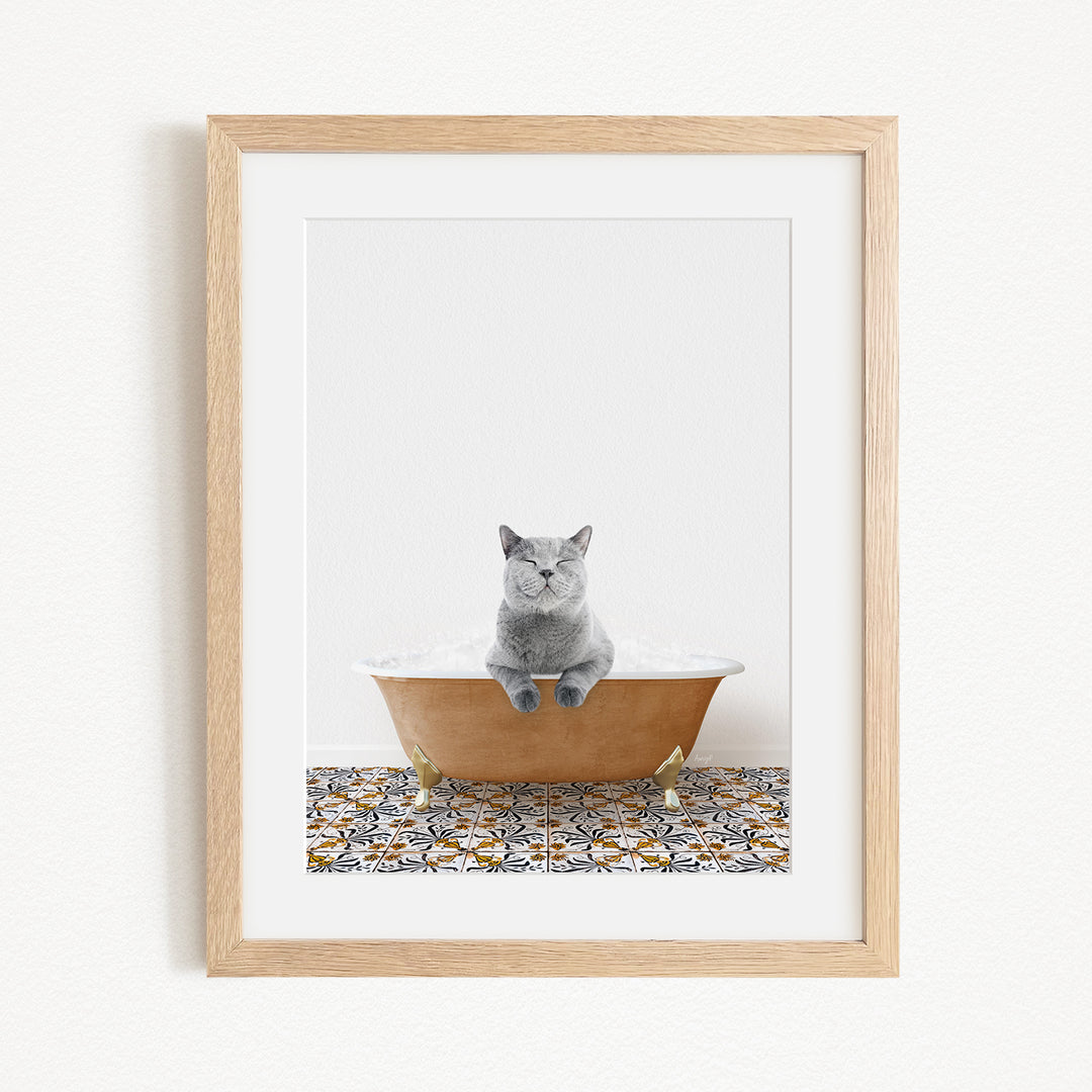 A gray cat sitting in a bathtub filled with bubbles, with a patterned tile floor beneath it.