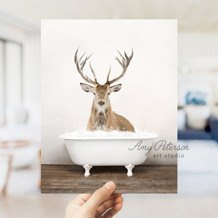 a hand holding up a photo of a deer in a bathtub