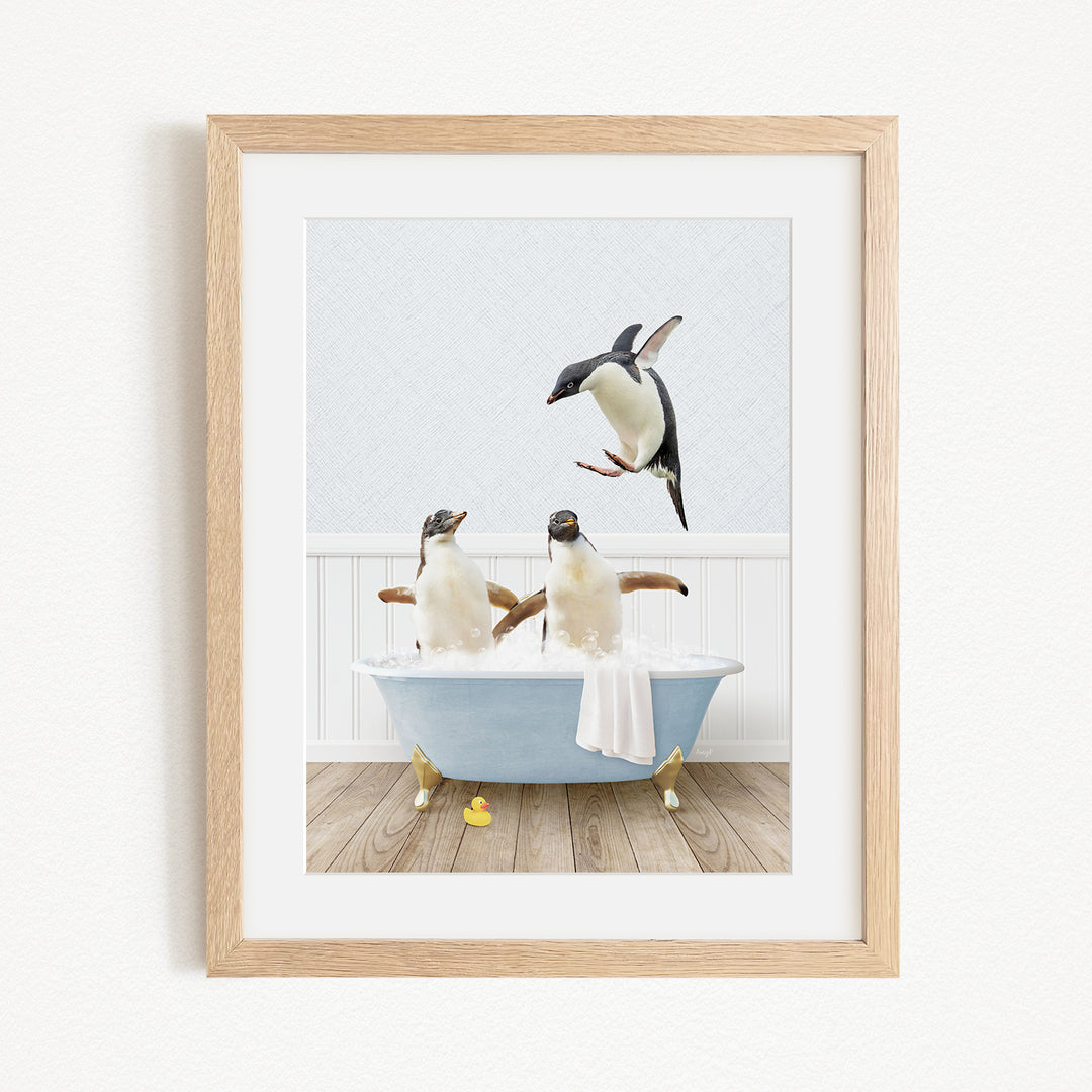 A framed image depicting two penguins sitting in a bathtub, with one penguin flying towards the other.