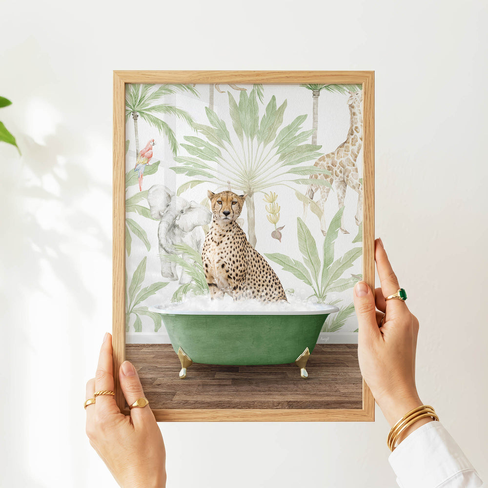 A person's hands are holding a framed picture of a cheetah sitting in a green bathtub, surrounded by tropical foliage.