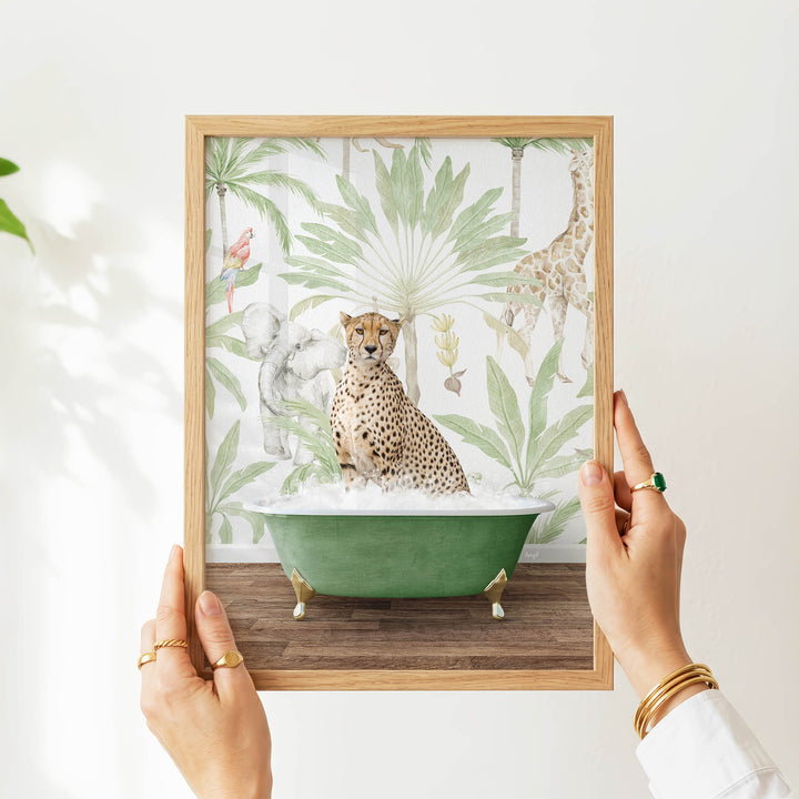 A person's hands are holding a framed picture of a cheetah sitting in a green bathtub, surrounded by tropical foliage.